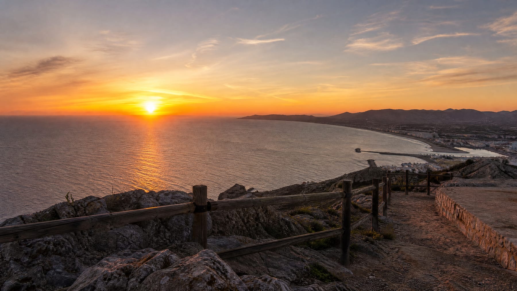 Hyper-realistic sunset in Cullera with golden sky over the sea and the lighthouse silhouette