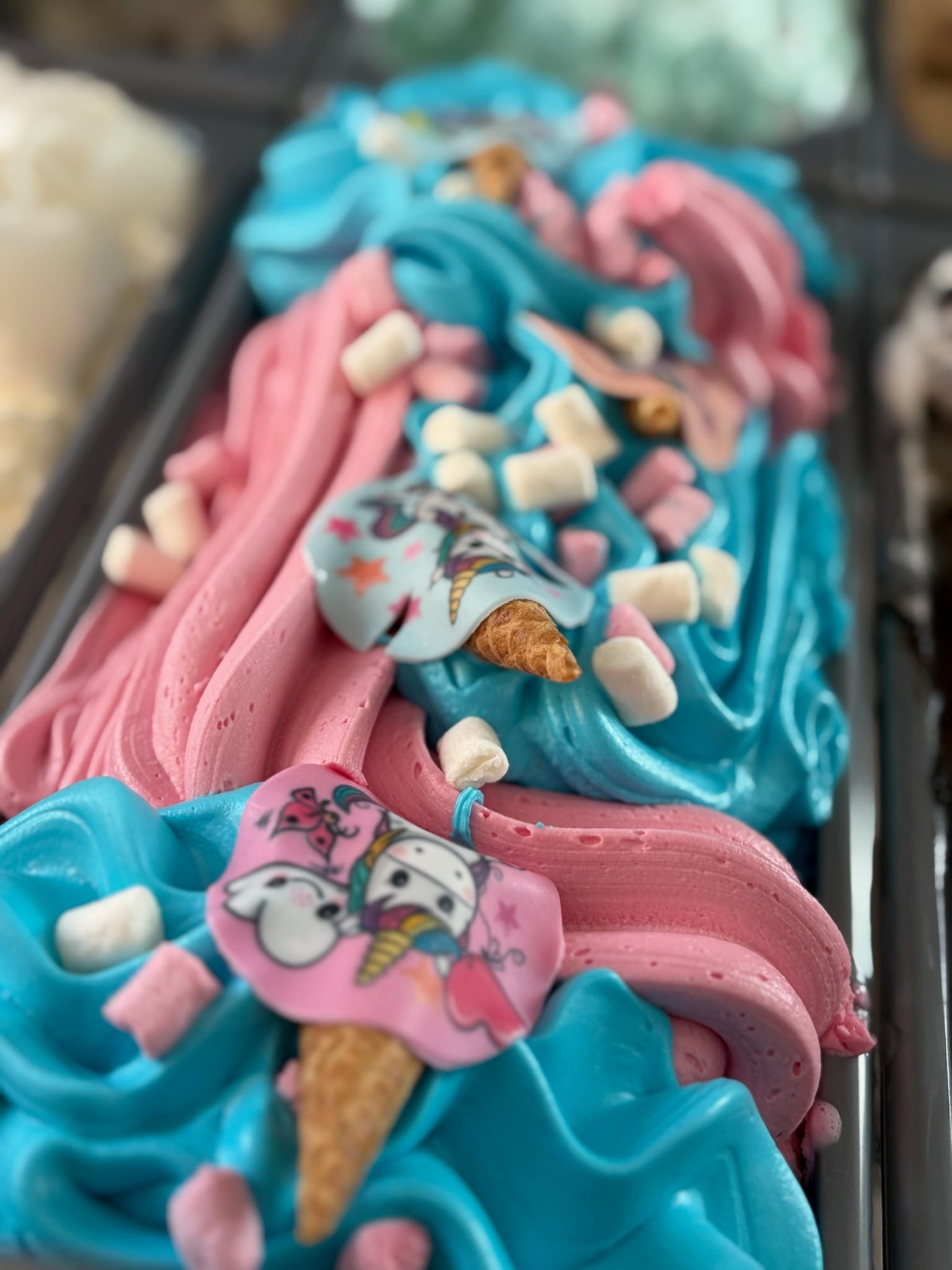 Kids’ ice cream with pink and blue swirls, mini marshmallows and unicorn-printed wafer toppers